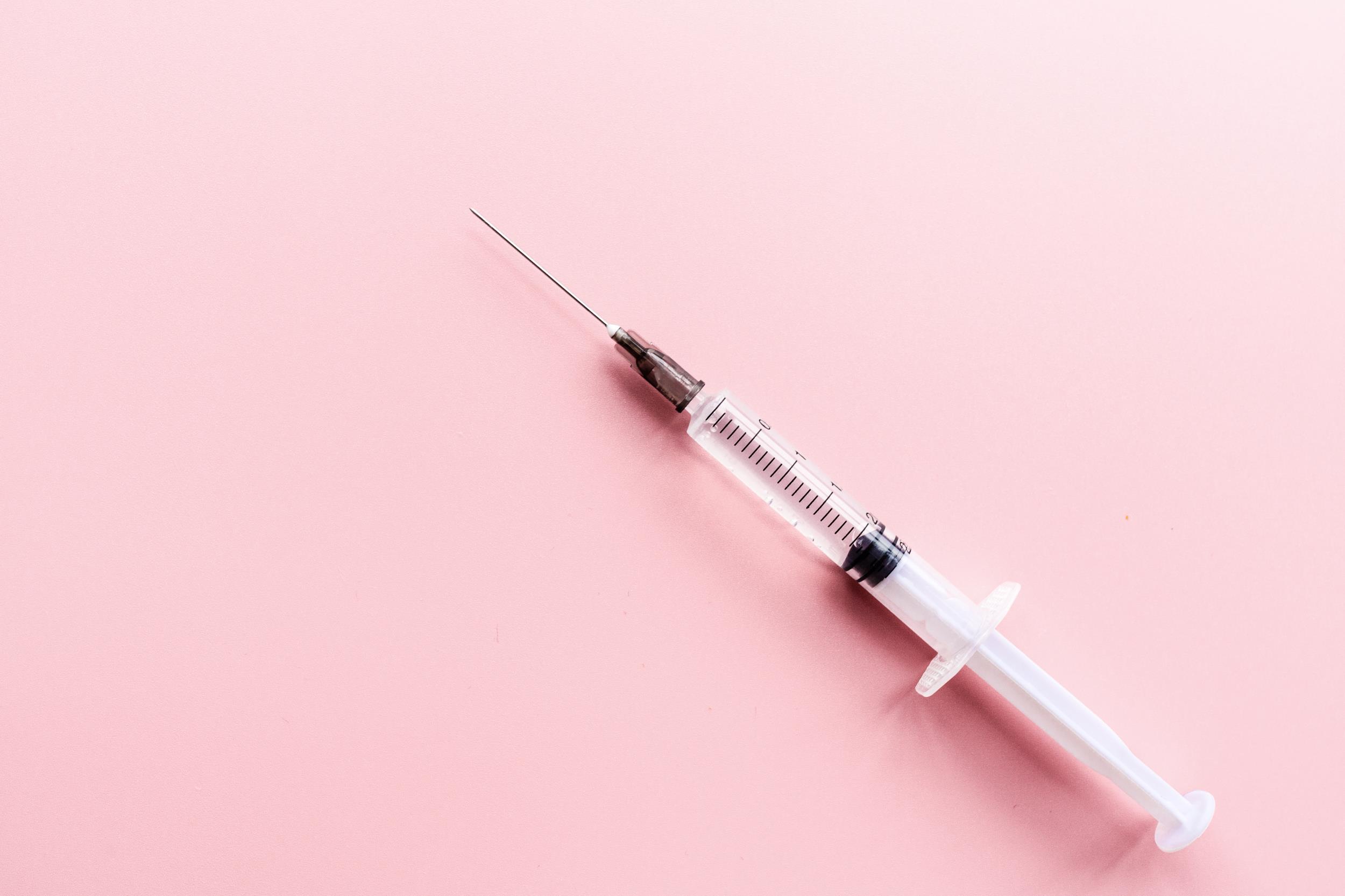 an empty syringe on a pink background