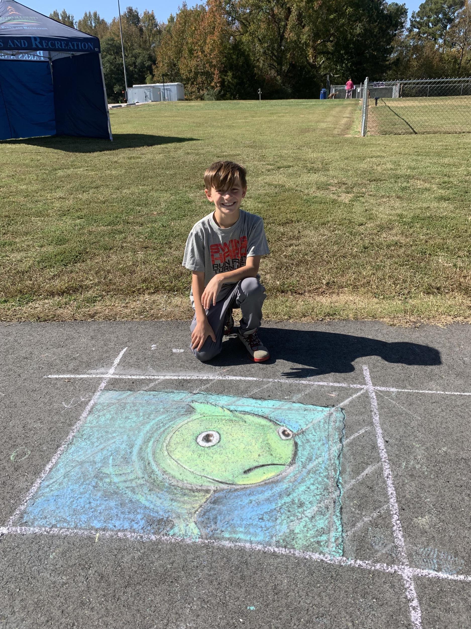 Sidewalk Chalk Festival - boy draws fish out of chalk