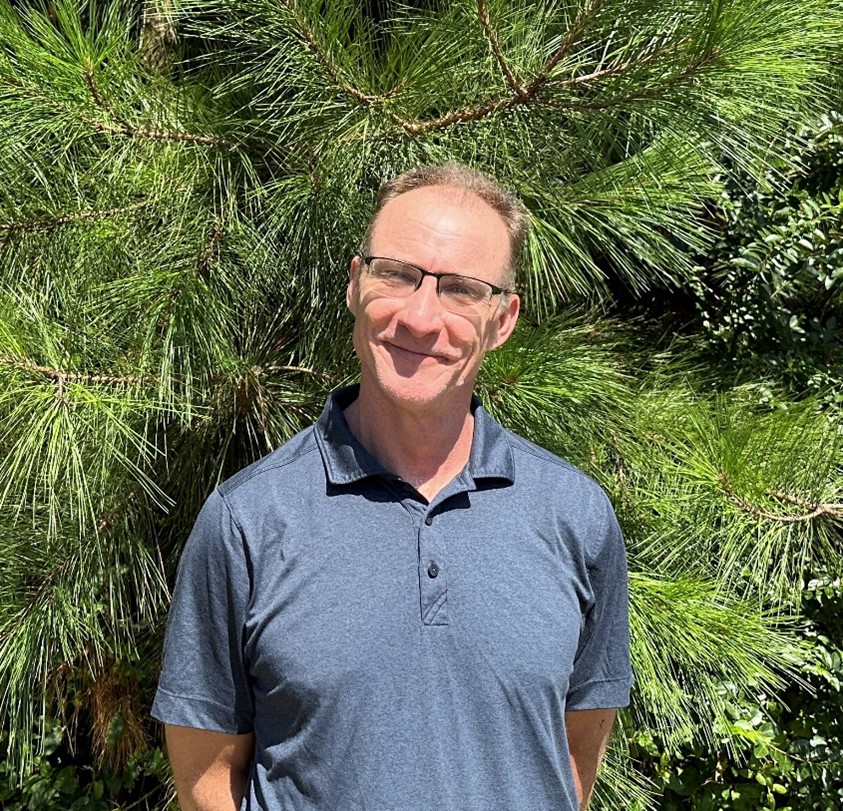 Andrew Waters Farmland Preservation Coordinator, man standing in front of pine trees