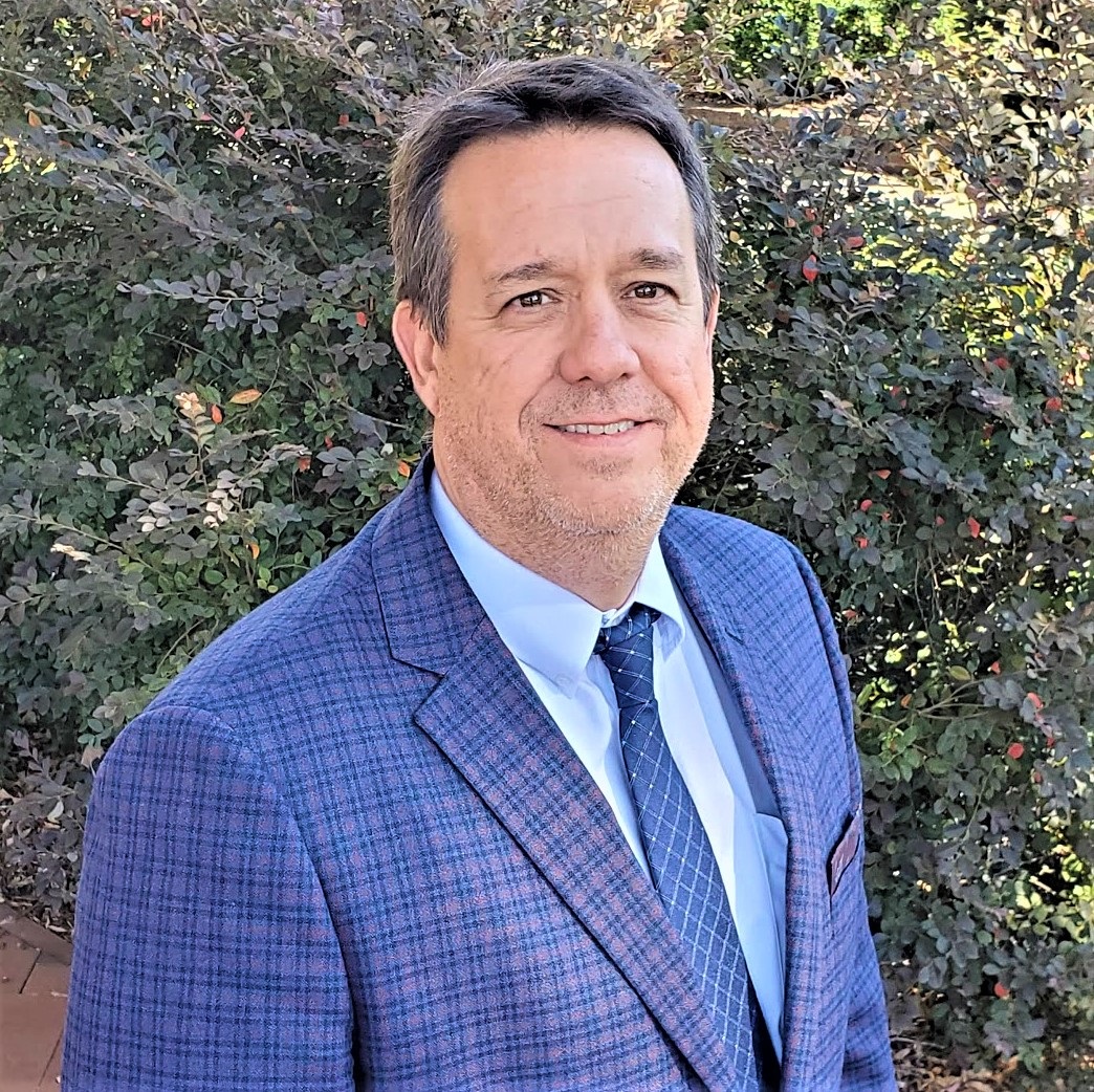 Image of Dan LaMontagne- White male with dark hair, blue suit jacket and tie. In front of tree.