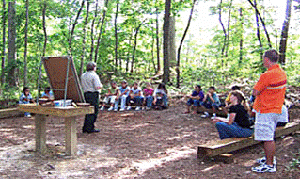 An instructor speaks to a class in an outdoor learning center.